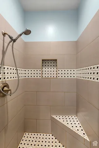 Shower stall with large format wall tiling, a decorative mosaic accent band, and a built-in bench