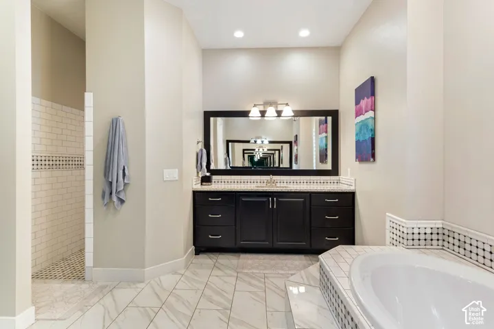 Spacious bathroom featuring a dark wood vanity with a light-colored countertop, an undermount sink, and an expansive framed mirror