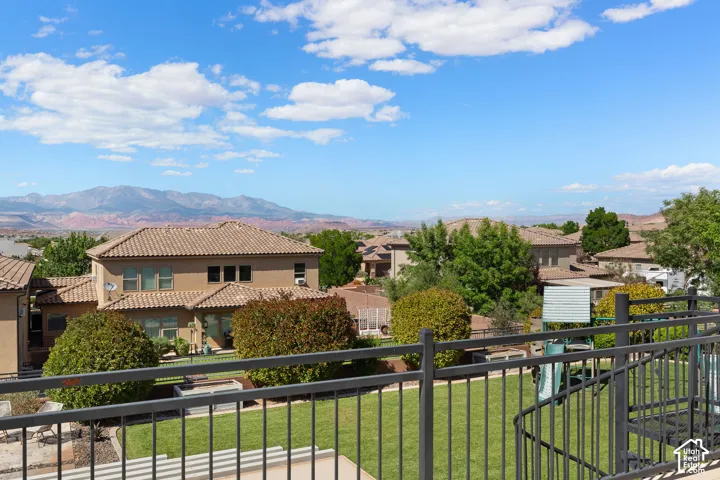 Expansive outdoor space featuring a manicured lawn, established landscaping, and a wrought iron railing