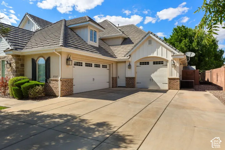 Stucco and stone exterior with brick accents and a multi-car driveway