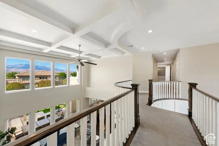 Upper-level hallway featuring a curved railing with dark wood and white balusters