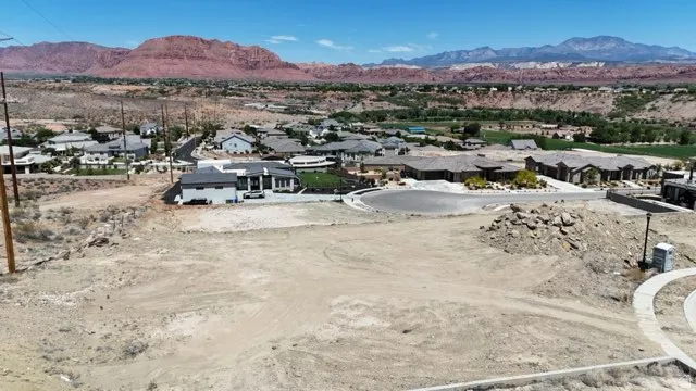 Expansive undeveloped lot featuring surrounding residential properties and distant mountain ranges