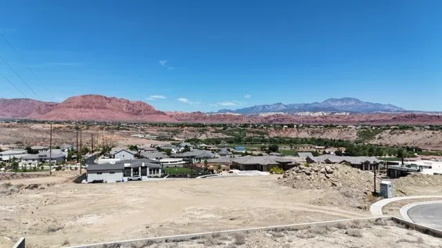 Expansive vacant lot featuring a paved cul-de-sac street and a mountainous backdrop