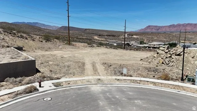 Vacant land parcel featuring a curved street frontage, existing sidewalks, and established infrastructure including power poles and a fire hydrant