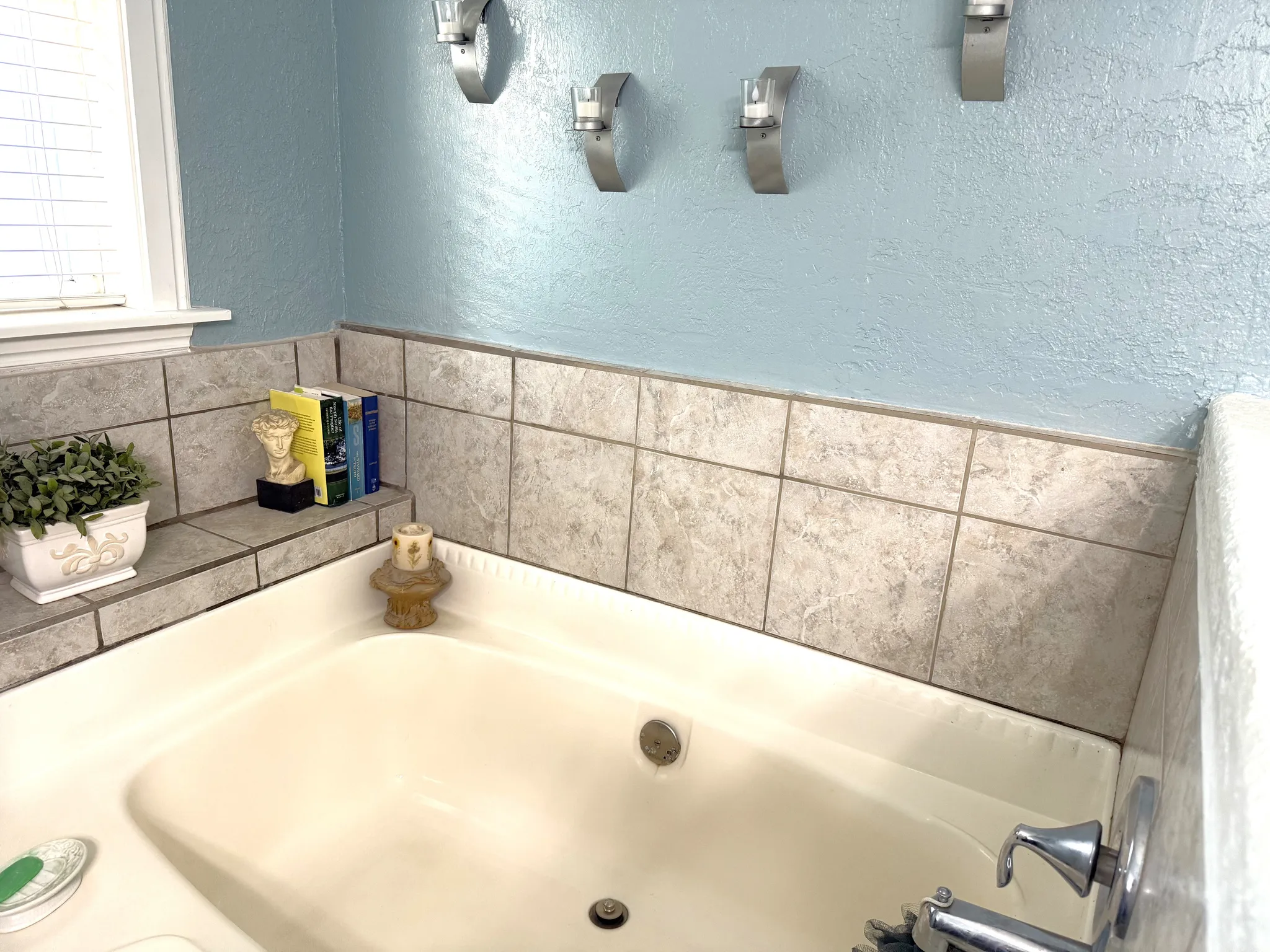 Built-in soaking tub featuring a tiled surround and chrome fixtures