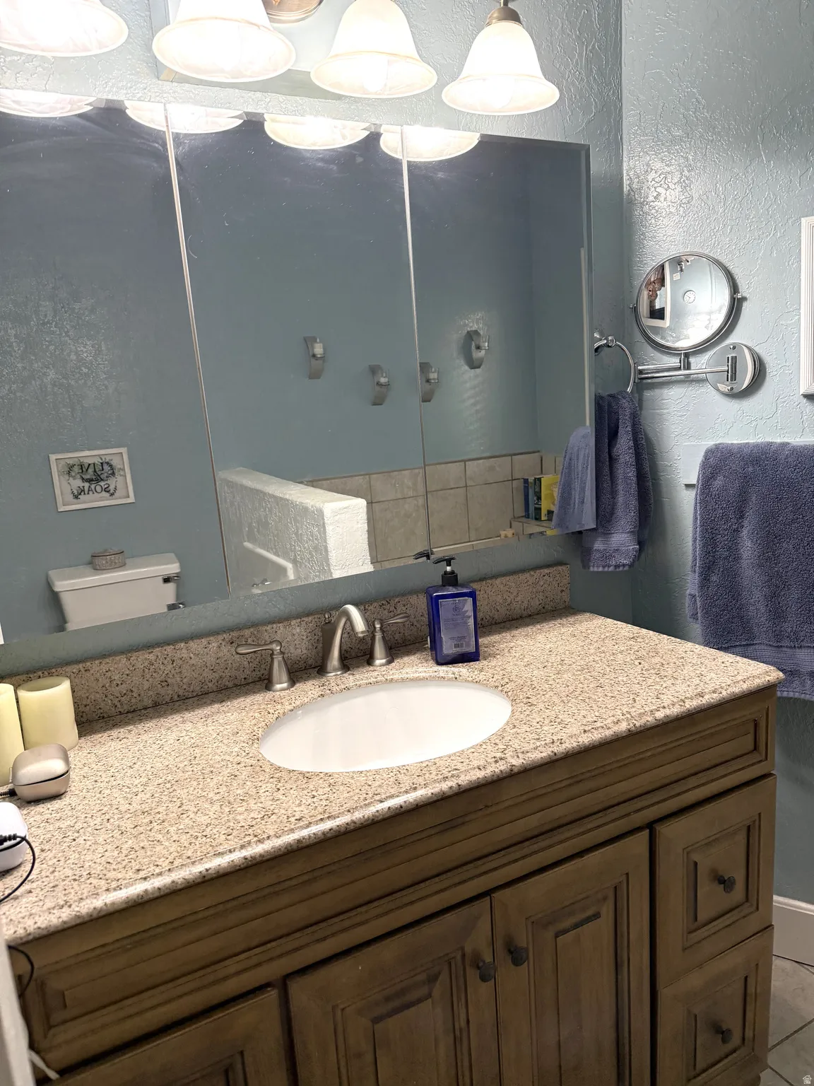 Bathroom vanity featuring a light-toned countertop, an oval undermount sink, and a brushed nickel faucet
