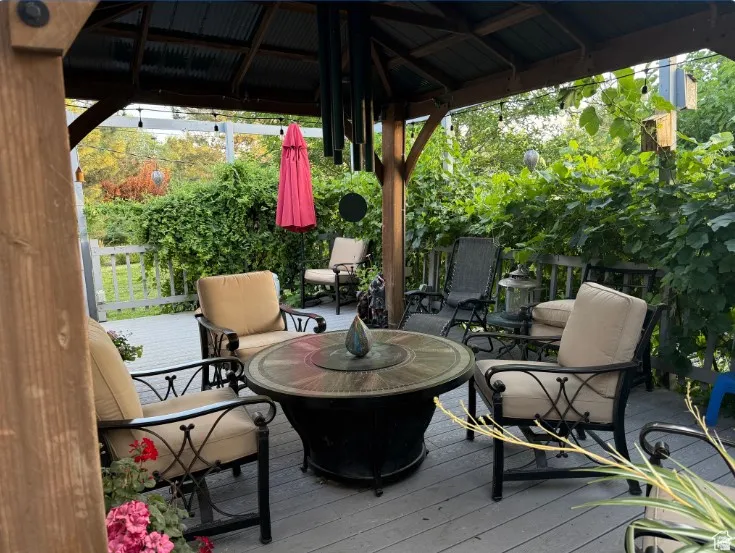 Covered outdoor deck area featuring a wood gazebo structure with a corrugated metal roof. Newer Trex deck with grapevines and honeysuckle giving cooling shade.