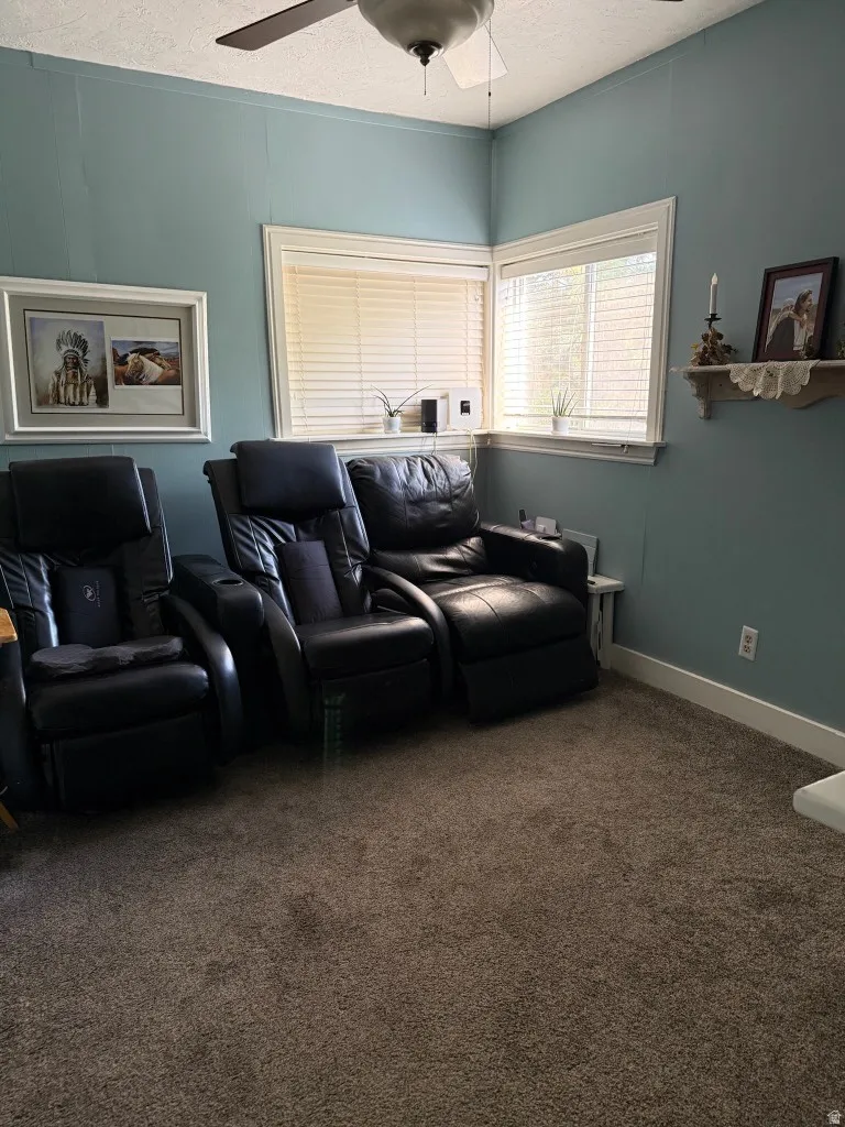 Corner room featuring two windows with blinds, a ceiling fan, and carpet flooring