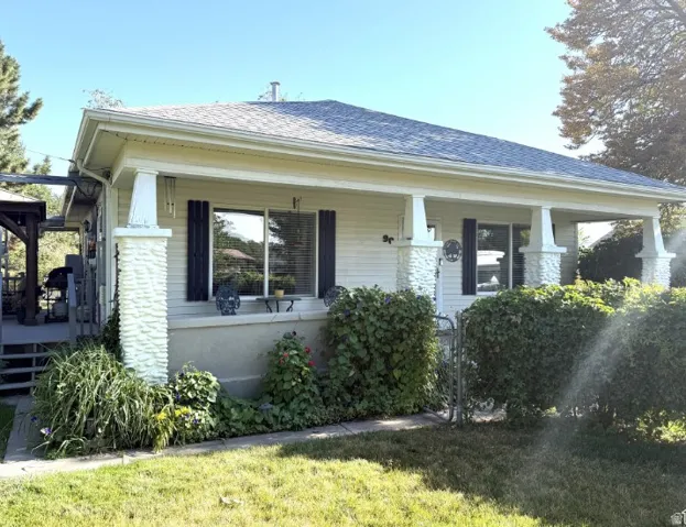 Front exterior featuring a covered porch with historic stone pillars and a  newer gray shingle roof