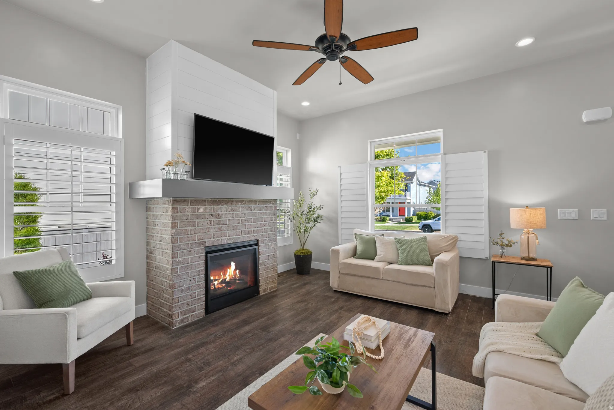 Vibrant living space featuring a brick-clad fireplace with a shiplap accent wall, wood-finish flooring, a ceiling fan, and recessed lighting