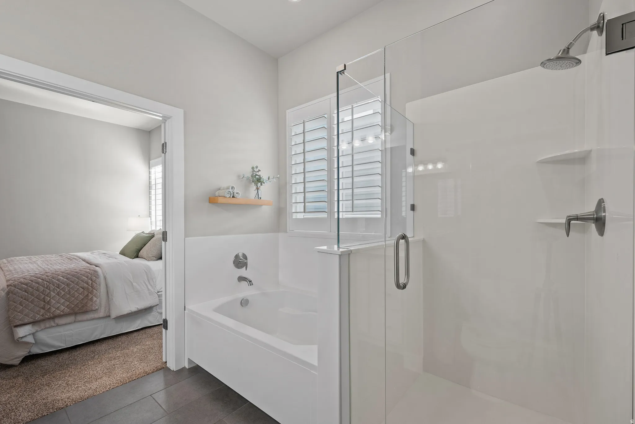 Modern bathroom featuring a walk-in shower with clear glass enclosure and rainfall showerhead, a separate soaking tub, and window with plantation shutters