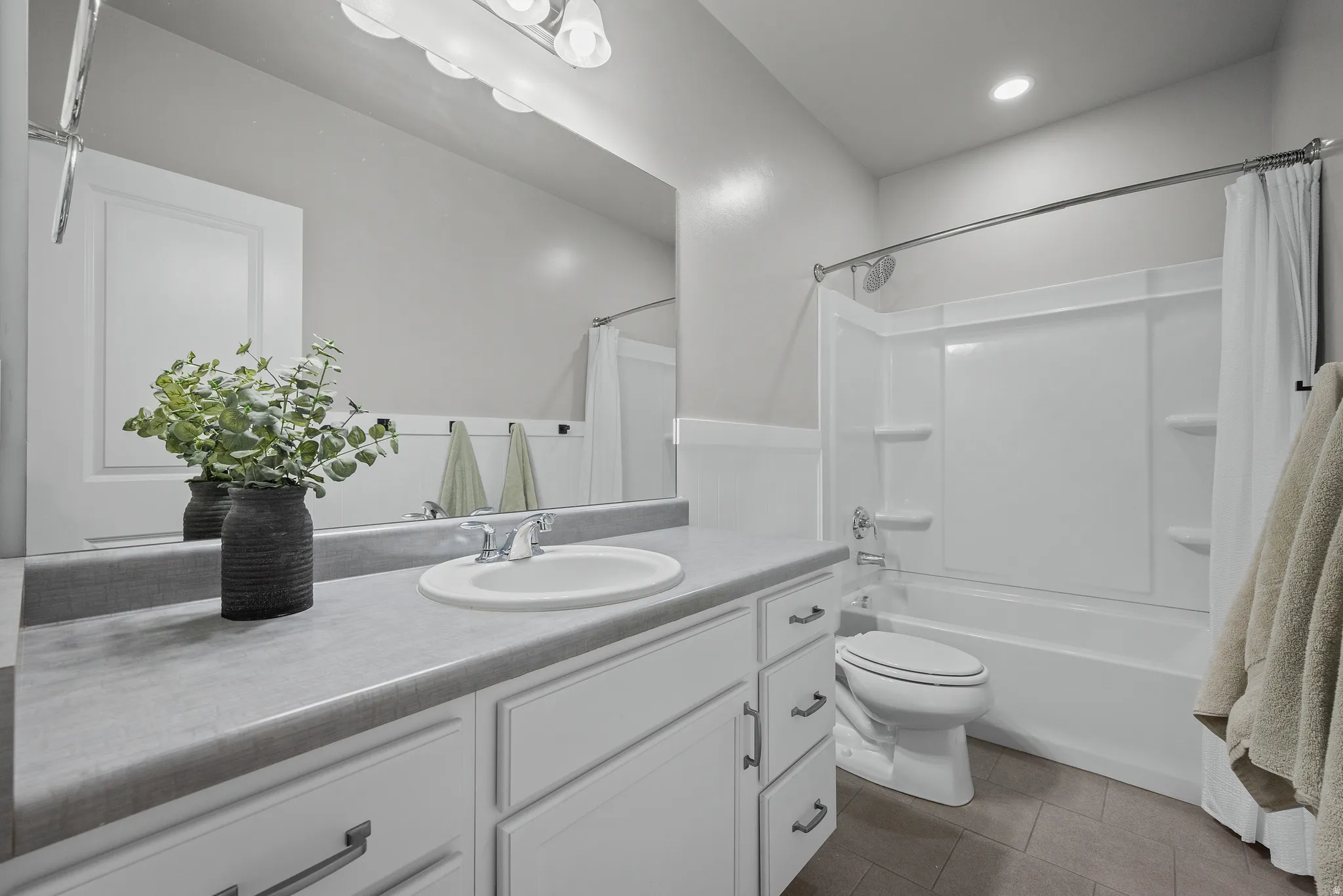 Bathroom vanity featuring a single basin sink, laminate countertop, and white cabinetry