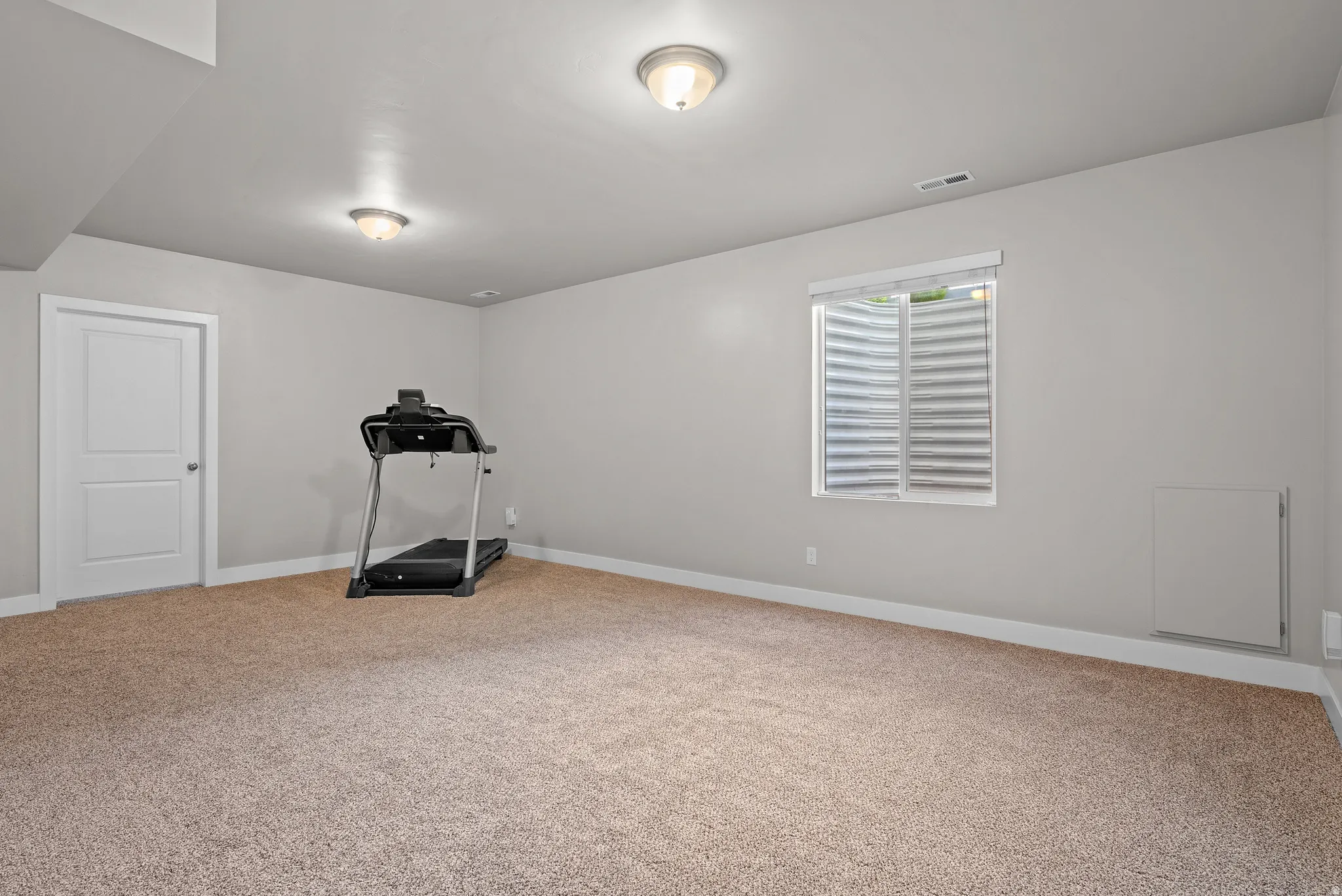 Spacious room featuring neutral carpeting, light gray wall paint, and white trim