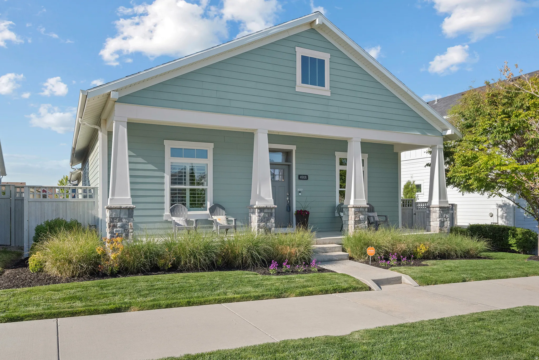 Light blue siding facade with white trim and a covered front porch featuring stone-wrapped columns