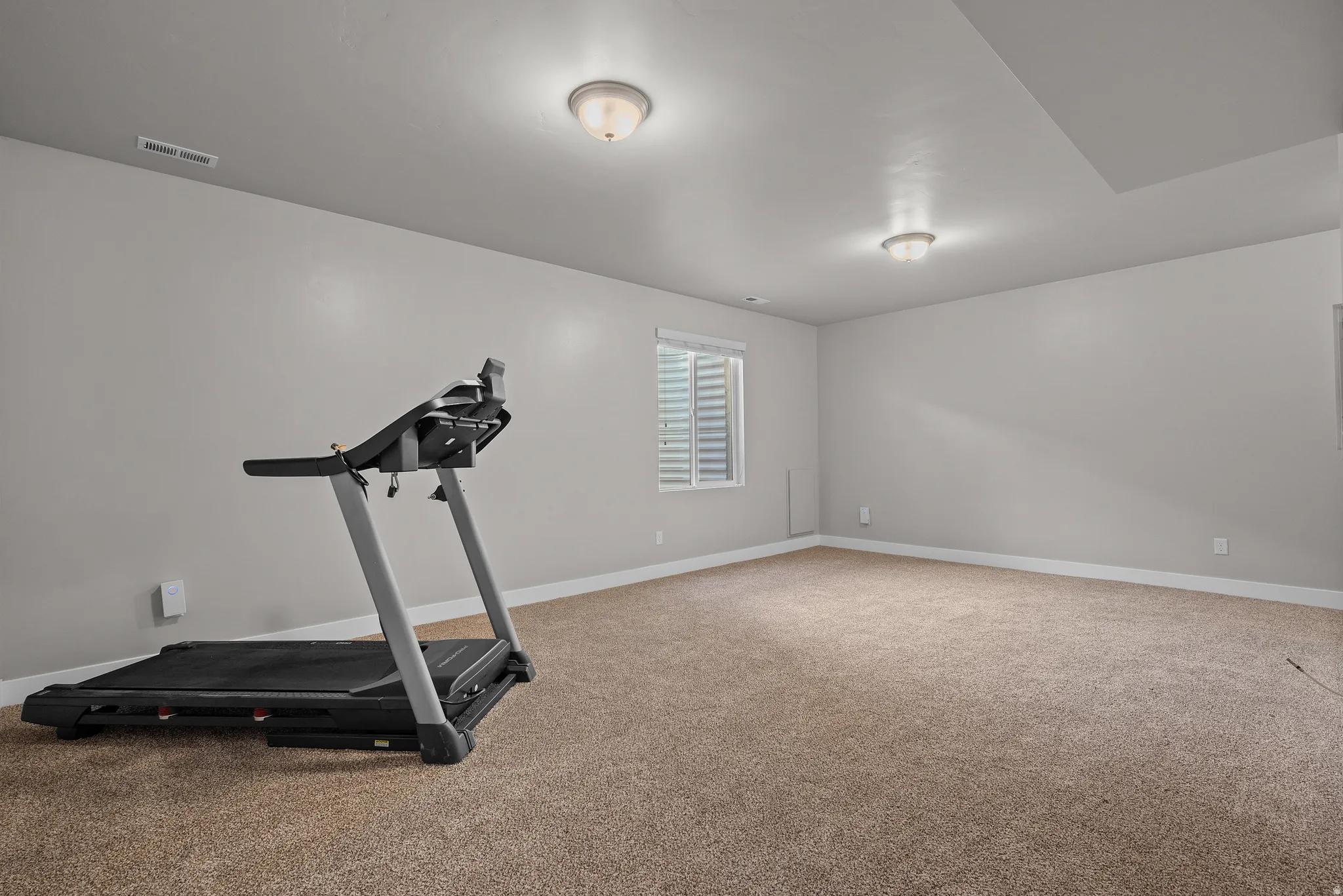 Versatile carpeted room with neutral wall tones, recessed lighting, and a window with blinds