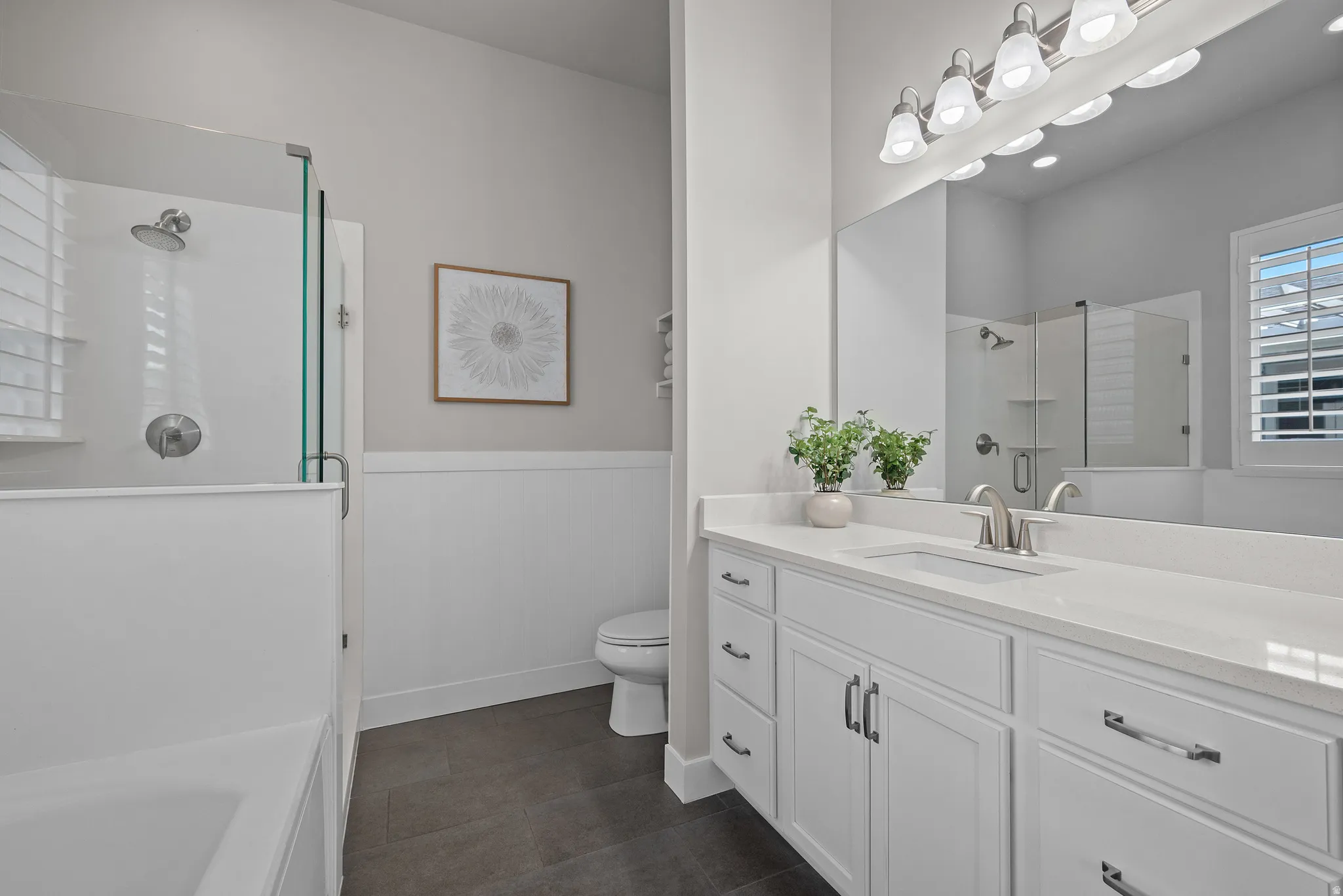 Contemporary bathroom featuring a spacious vanity with dual sinks, white cabinetry, and a light-colored countertop