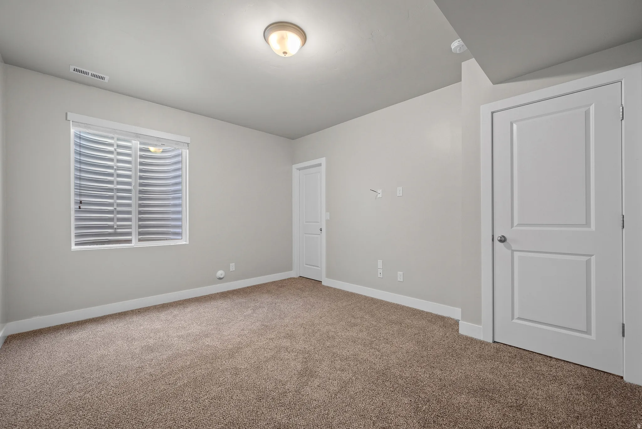Neutral-toned interior room featuring light gray walls, plush brown carpeting, and white trim