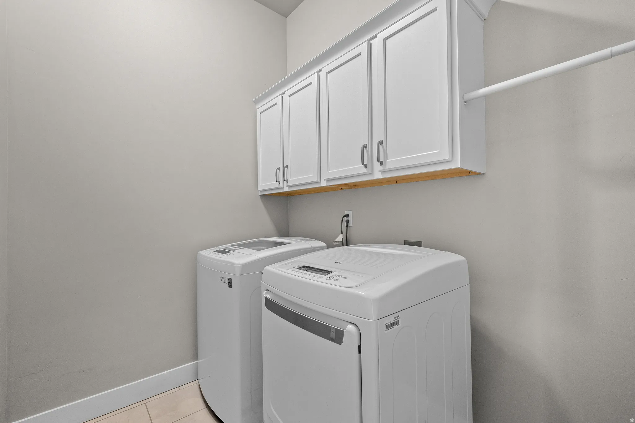 Laundry area featuring white cabinetry, a light wood-finish shelf, and a hanging rod