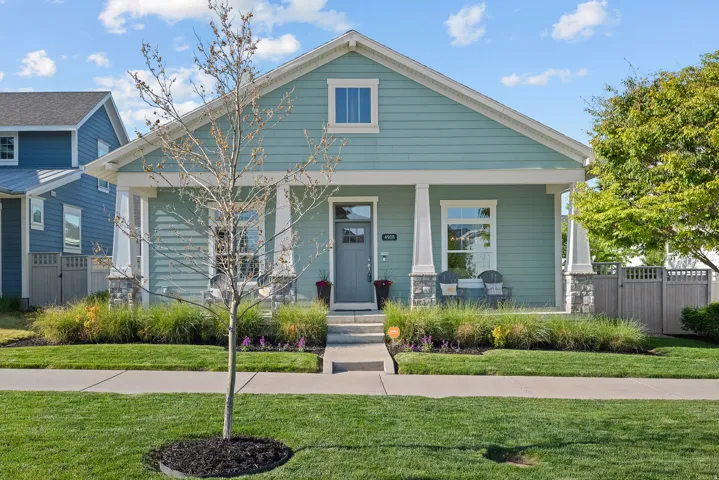 Craftsman-style home featuring a covered front porch with stone-clad columns, horizontal siding, and a gabled roofline