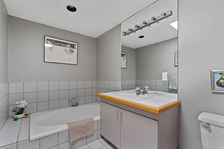 Bathroom featuring a built-in bathtub, a vanity with a laminate countertop, and an integrated sink