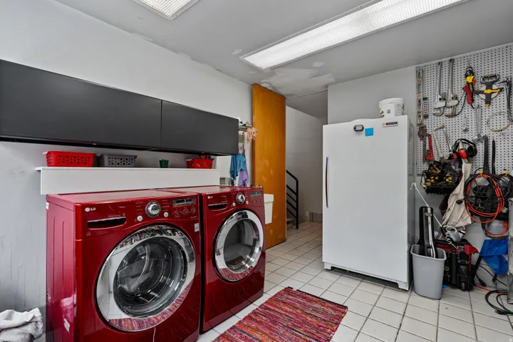 Dedicated utility space featuring a tiled floor, overhead fluorescent lighting, and a wall-mounted pegboard for organization