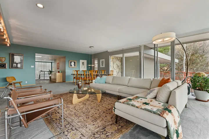 Open-concept living area with extensive floor-to-ceiling windows, recessed lighting, and a stone accent wall