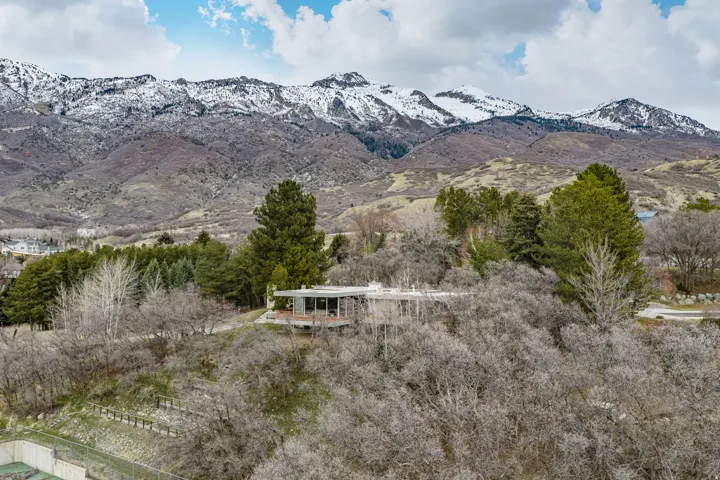 Modern residence featuring expansive glass walls, a flat roofline, and an elevated position