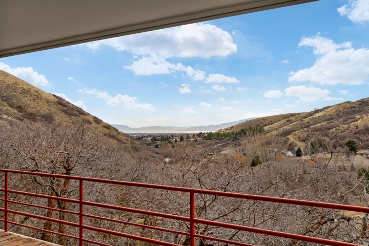 Outdoor balcony with red metal railing, offering expansive mountain and valley scenery