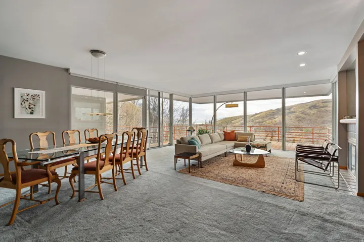 Open-concept living area with extensive floor-to-ceiling windows, gray wall paint, recessed lighting, and light gray carpeting
