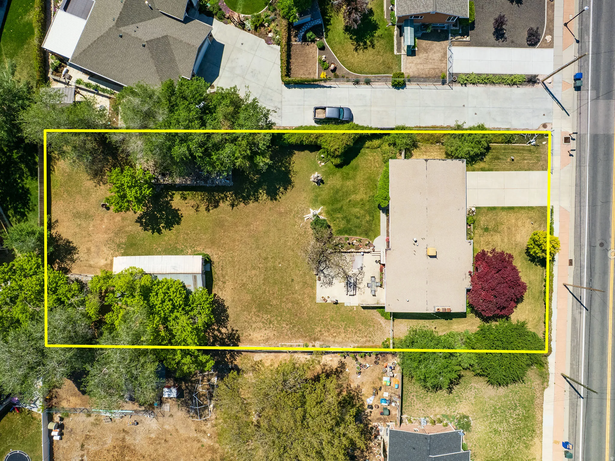 Spacious property with a large backyard, mature trees, and a detached storage shed