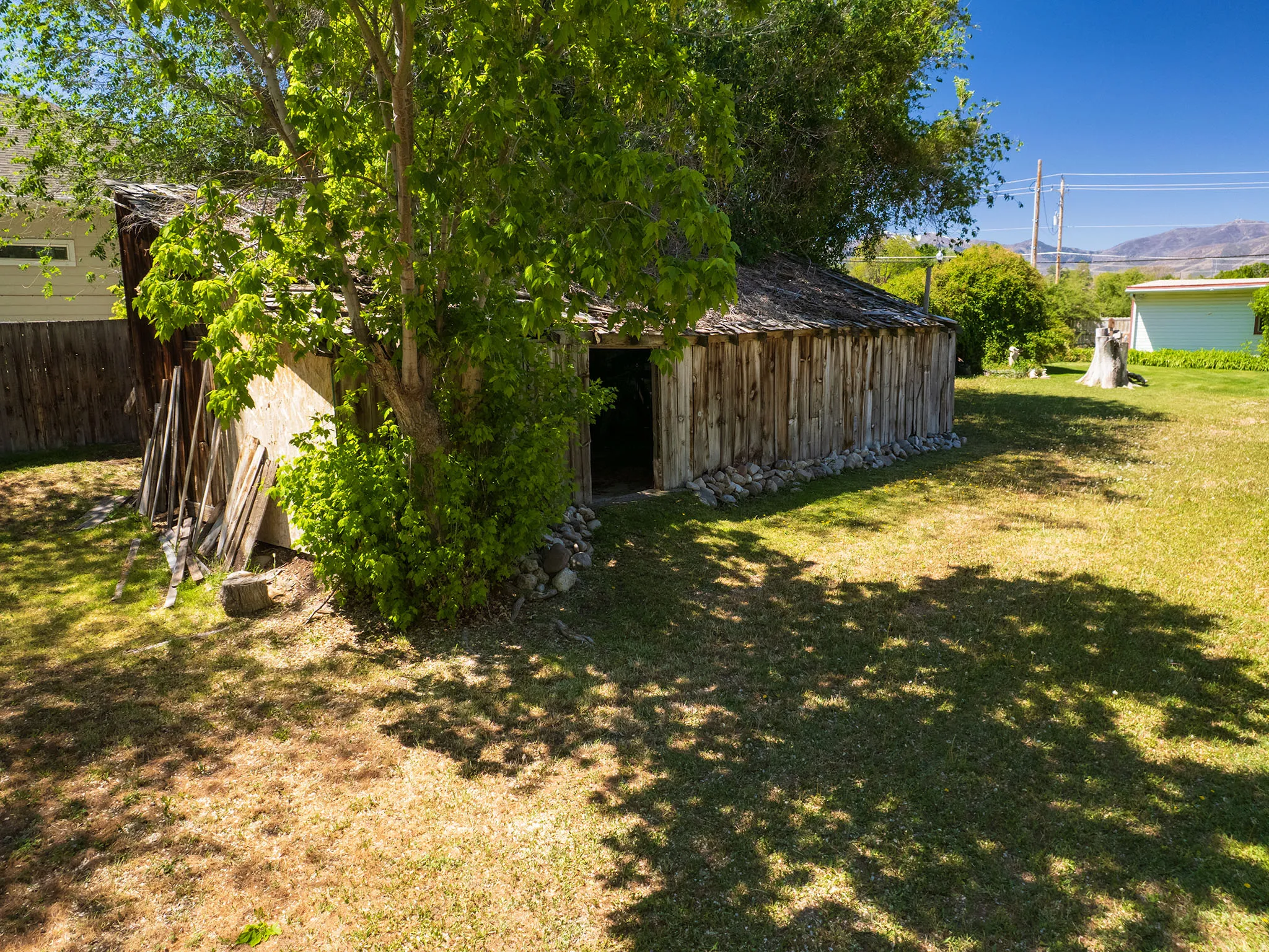 Rustic outbuilding featuring vertical wood siding, a wood-shingle roof, and a stone foundation