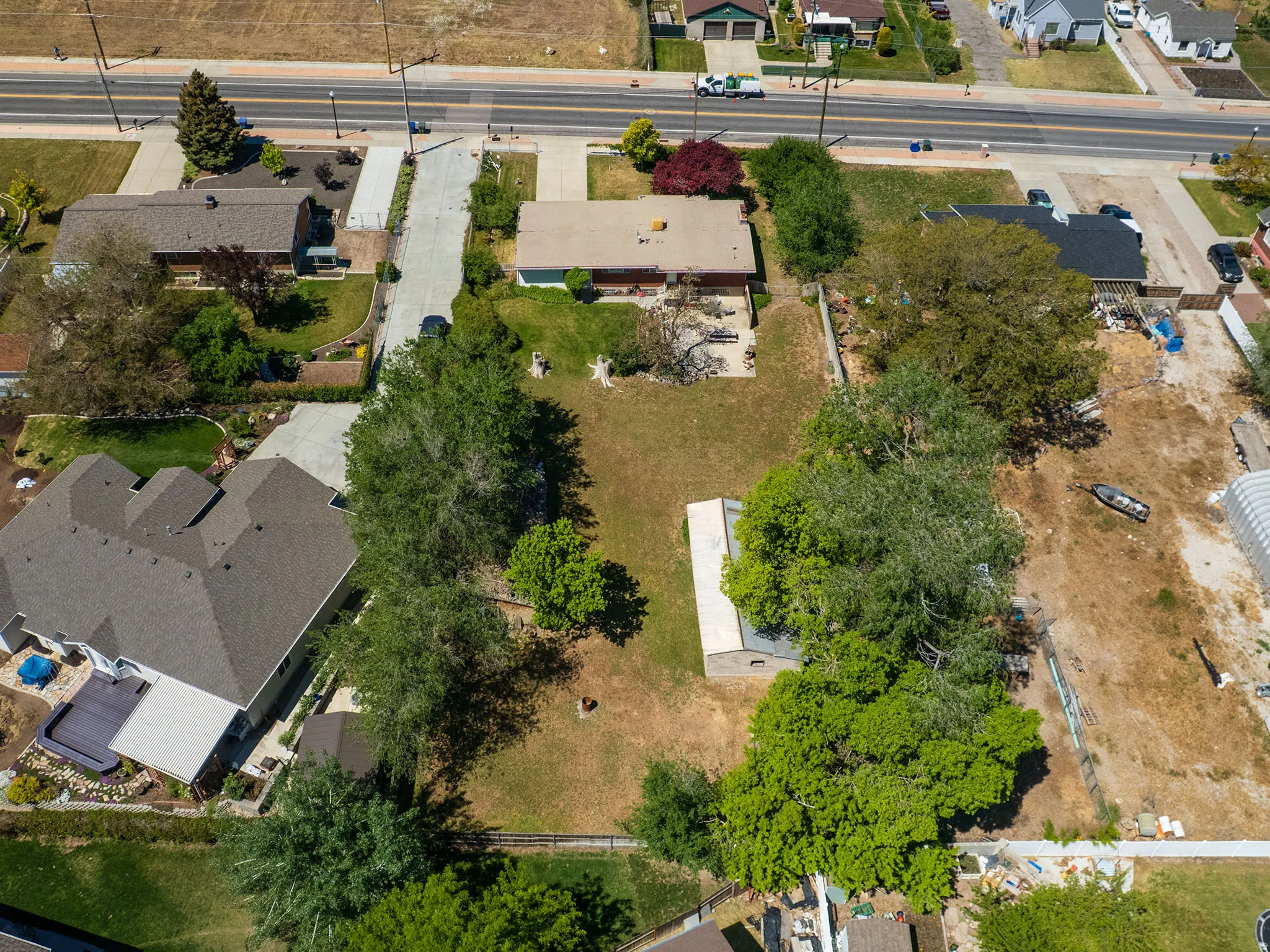 Expansive property featuring a central residence, mature trees, a detached outbuilding, and significant undeveloped land