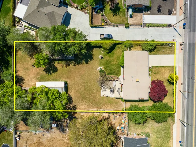 Spacious property with a large backyard, mature trees, and a detached storage shed