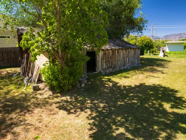 Rustic outbuilding featuring vertical wood siding, a wood-shingle roof, and a stone foundation