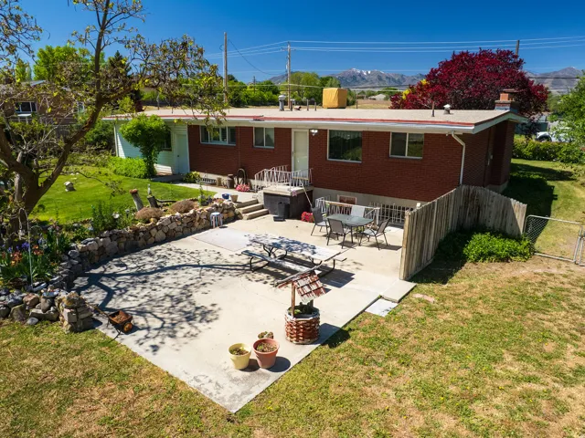 Rear exterior featuring a brick facade, white trim, and a concrete patio
