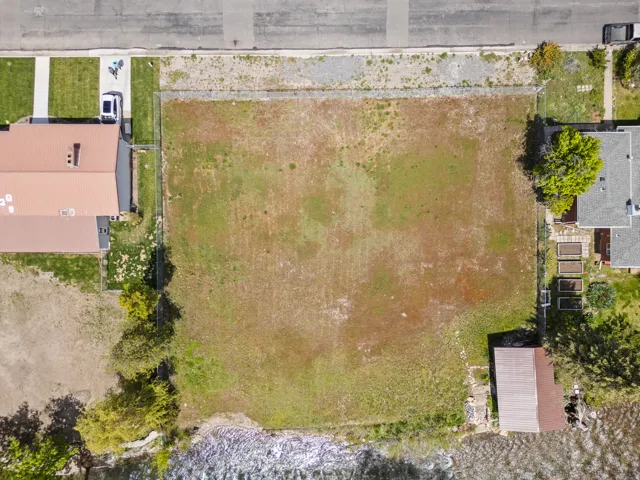 Expansive land parcel featuring natural ground cover, street frontage, and waterfront access
