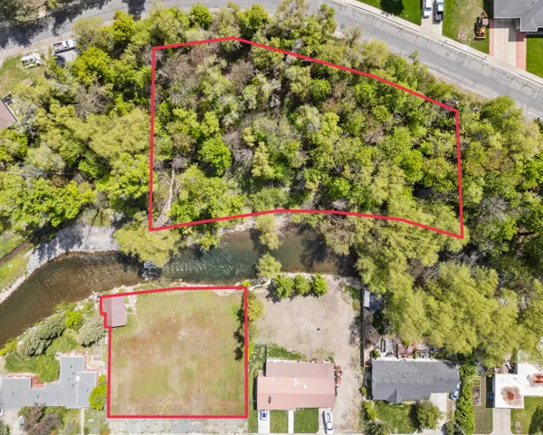 Expansive property featuring a riverfront boundary, mature tree coverage, and a cleared building area
