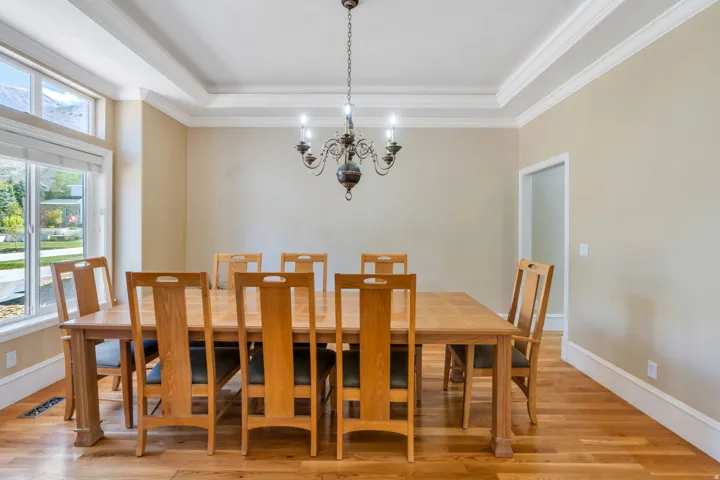 Dining area featuring wood-finish flooring, a multi-pane window, a chandelier, and a tray ceiling with crown molding