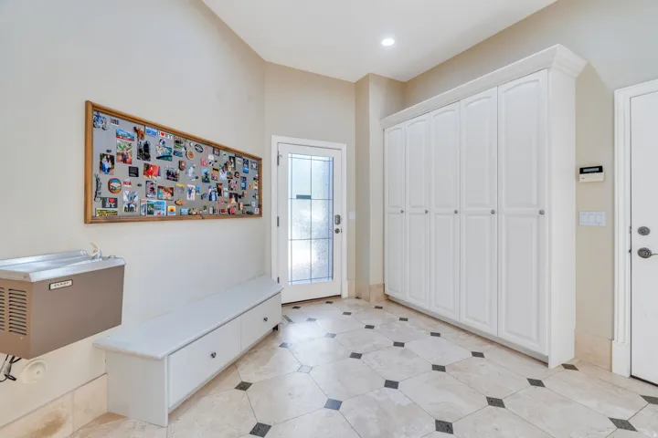 Entryway featuring extensive built-in cabinetry, decorative glass-paneled door, recessed lighting, and tile flooring with accent inserts