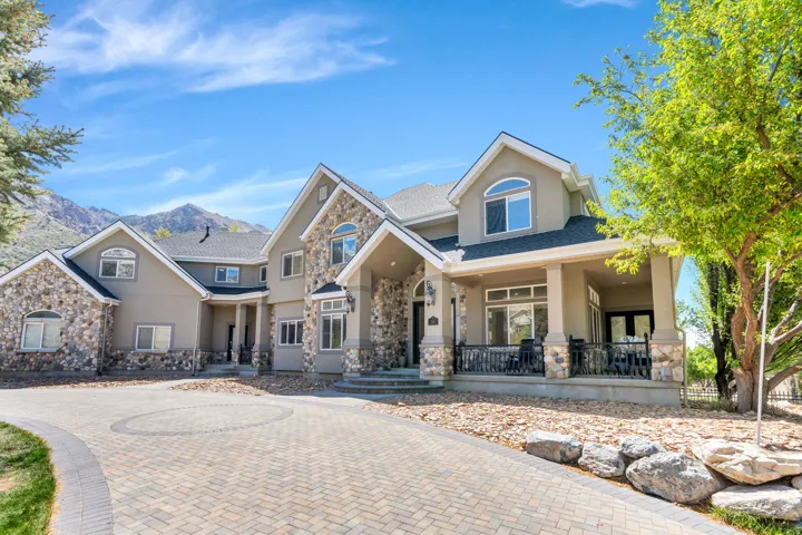 Stucco and stone exterior with multiple gables and a covered porch