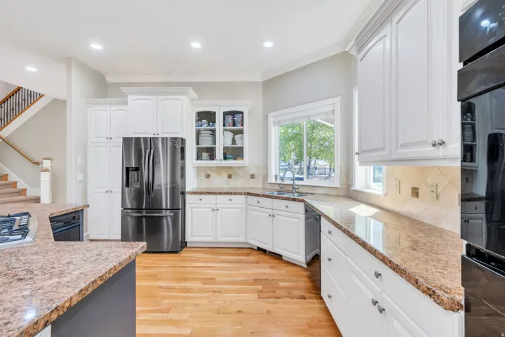 Kitchen featuring light wood-finish flooring, white cabinetry, granite countertops, and stainless steel appliances