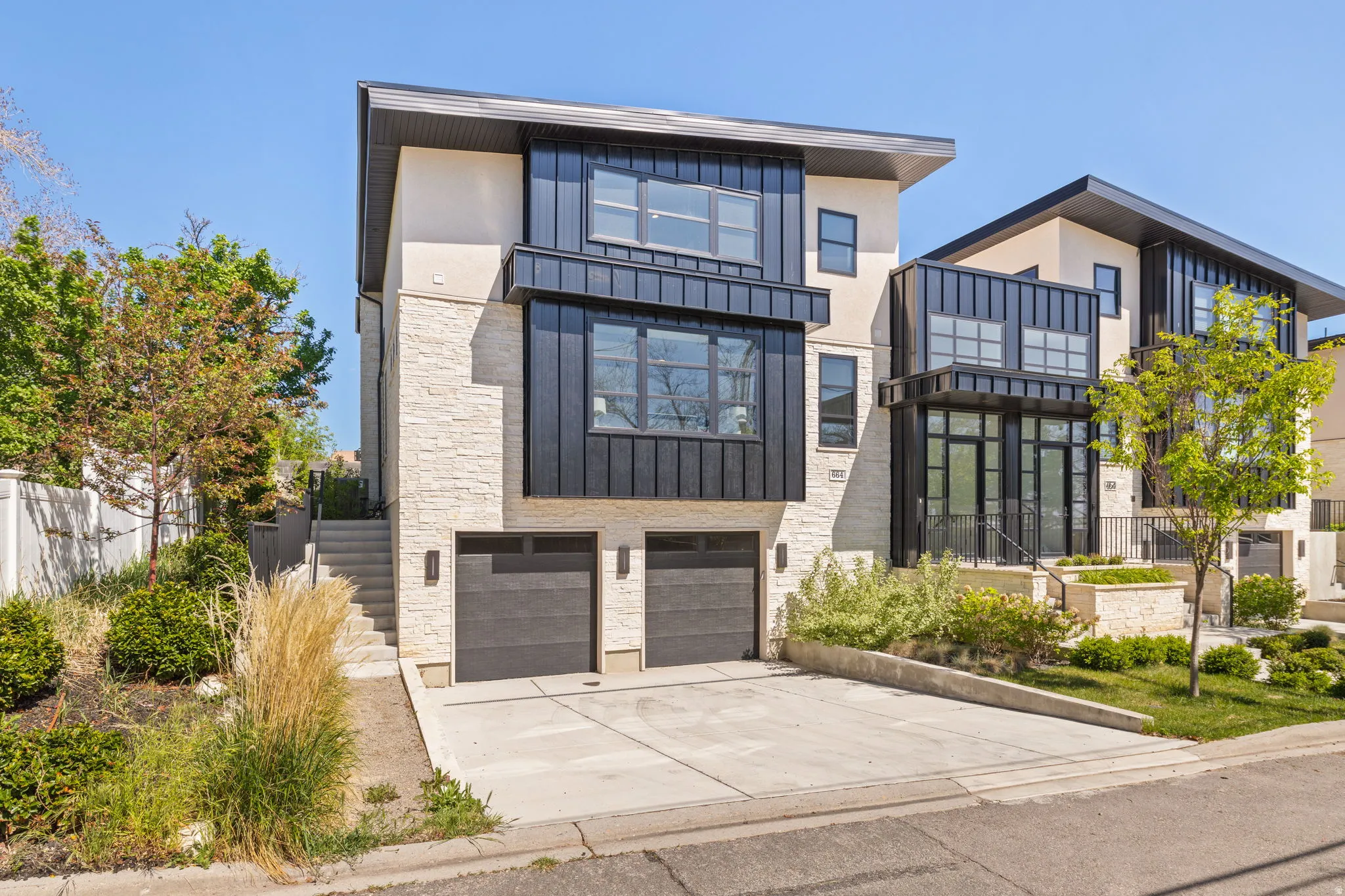 Contemporary multi-level exterior featuring light-colored stone and vertical dark metal siding