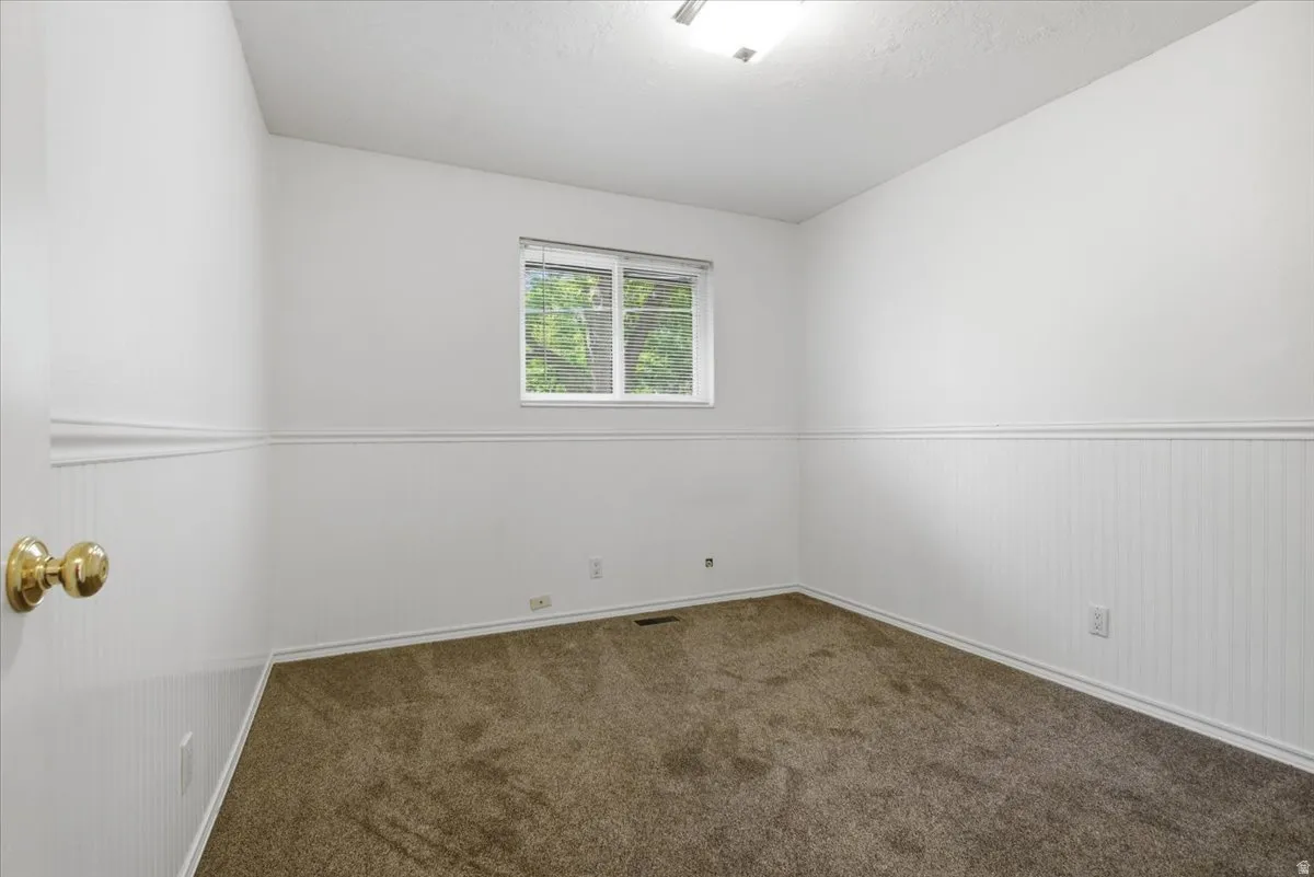 Carpeted room featuring white beadboard wainscoting, white baseboards, and a window with blinds