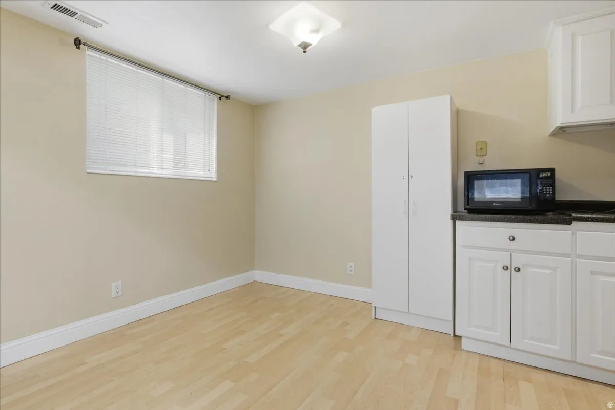 Compact kitchen area featuring white cabinetry, dark countertop, and a built-in microwave