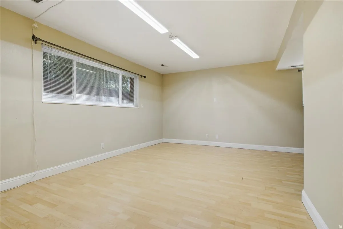 Spacious room featuring light wood-finish flooring, neutral wall tones, and white baseboards