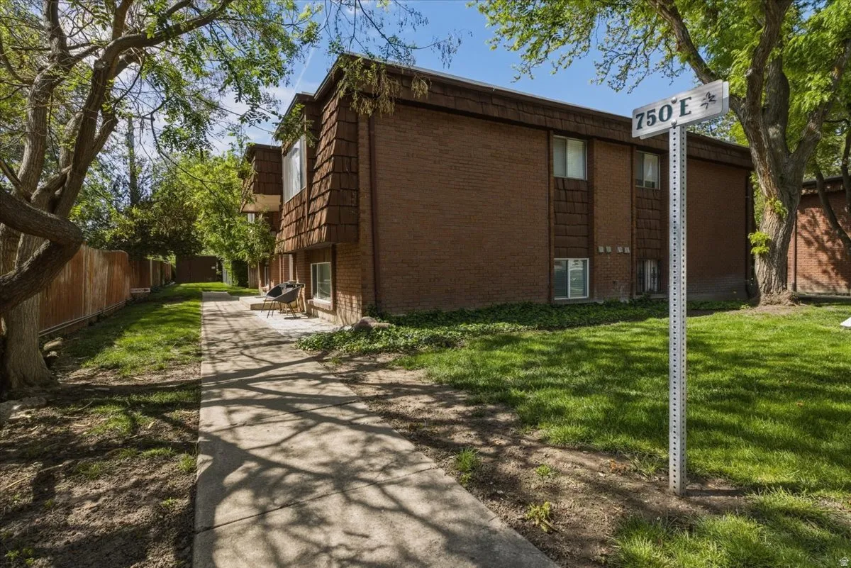 Brick exterior building with wood shingle accents, multiple windows, and a concrete patio