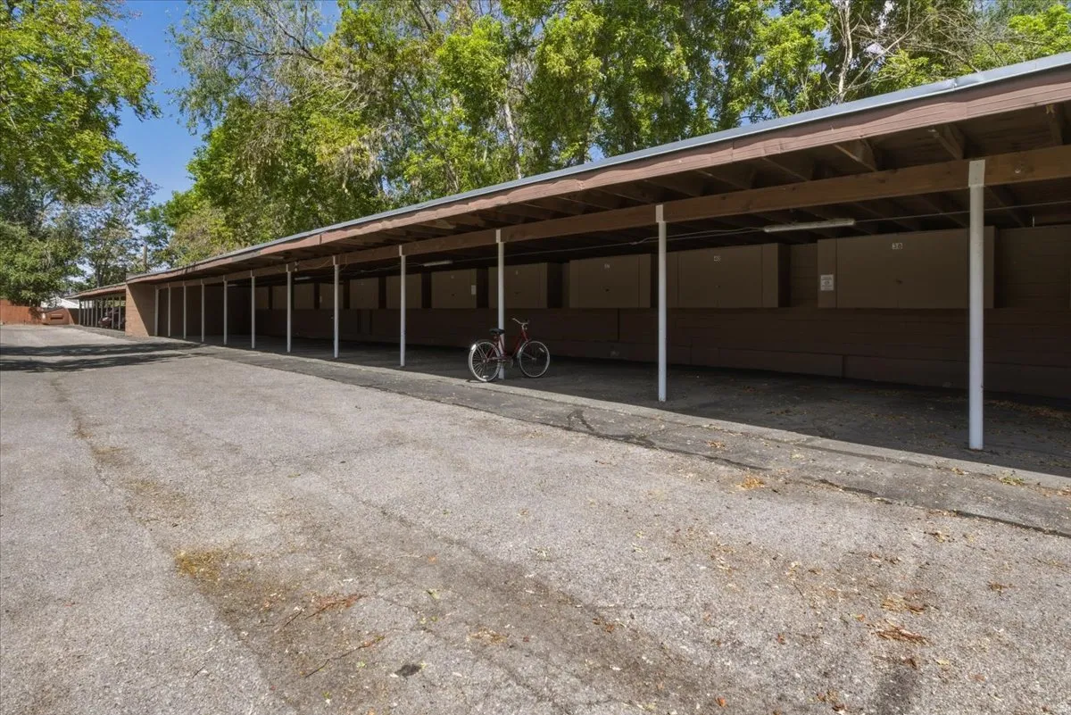 Covered parking structure featuring a brown wood-finish roof, white support columns, and individual storage units