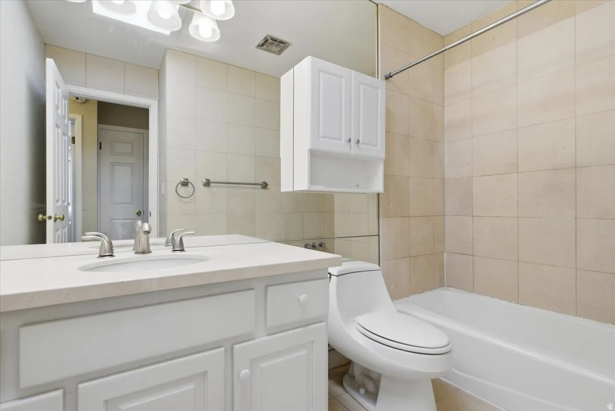 Bathroom featuring a white vanity with an undermount sink, a light-toned countertop, and a full-width mirror