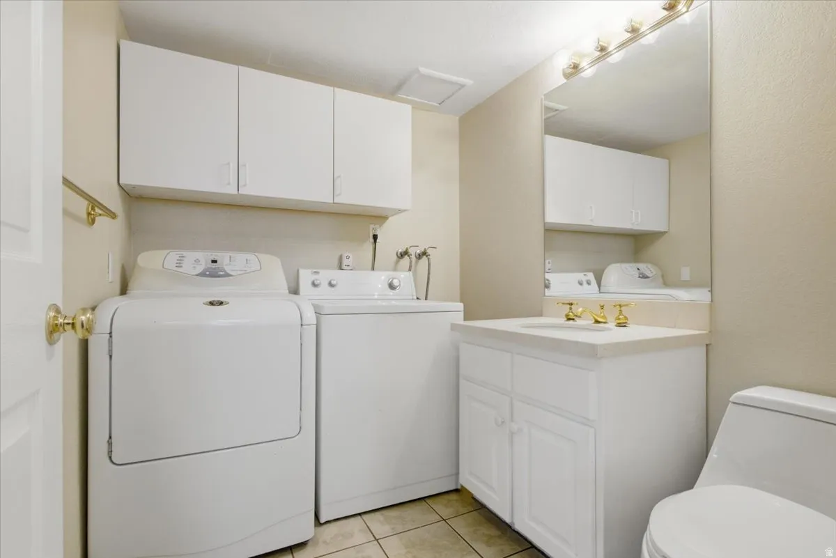 Laundry area with white cabinetry, a single vanity with a gold-tone faucet, a mirror, and a toilet