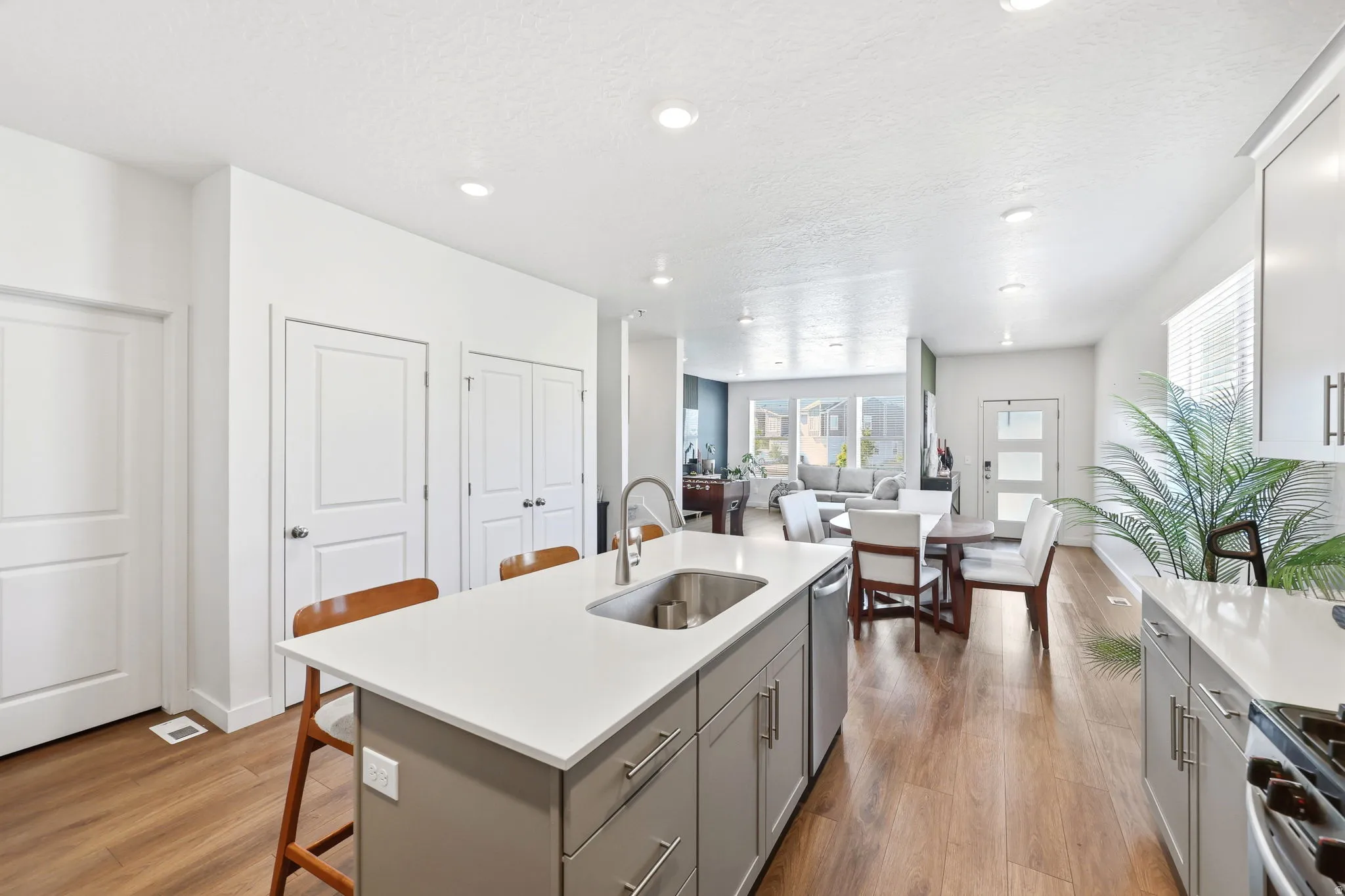 Kitchen island with integrated stainless steel sink, contemporary cabinetry, and wood-finish flooring